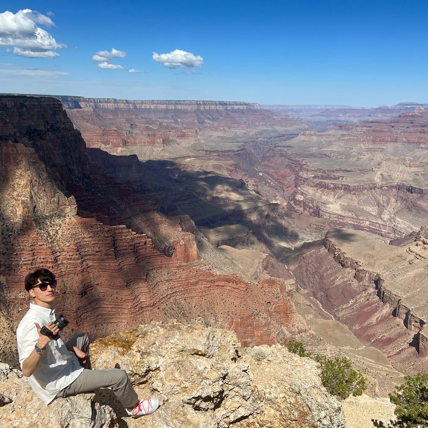 David holding a camera while seated above the Grand Canyon