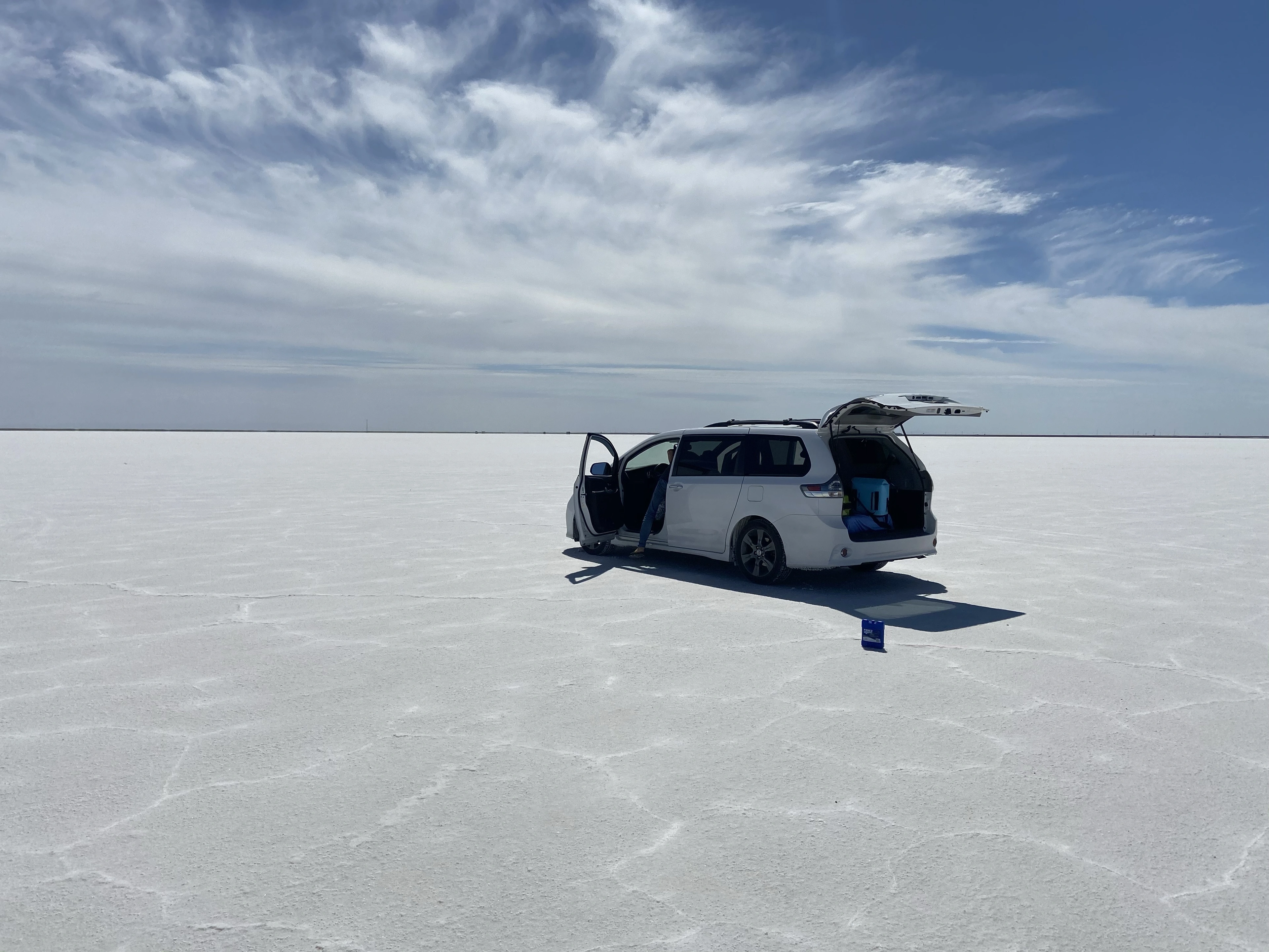 A white minivan beneath a wide sky on the Bonneville Salt Flats