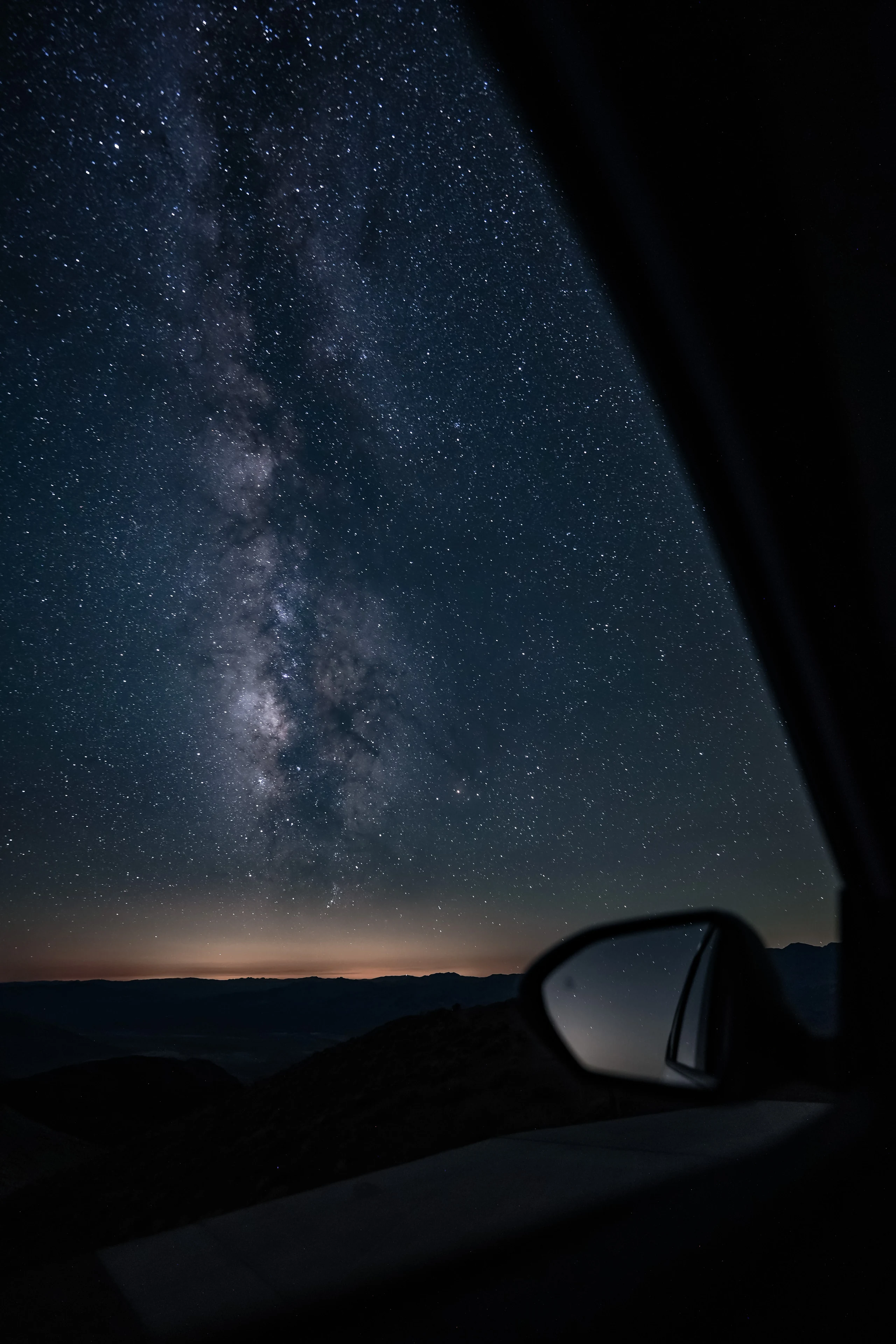 A vertical view of the Milky Way beside a car mirror in Death Valley