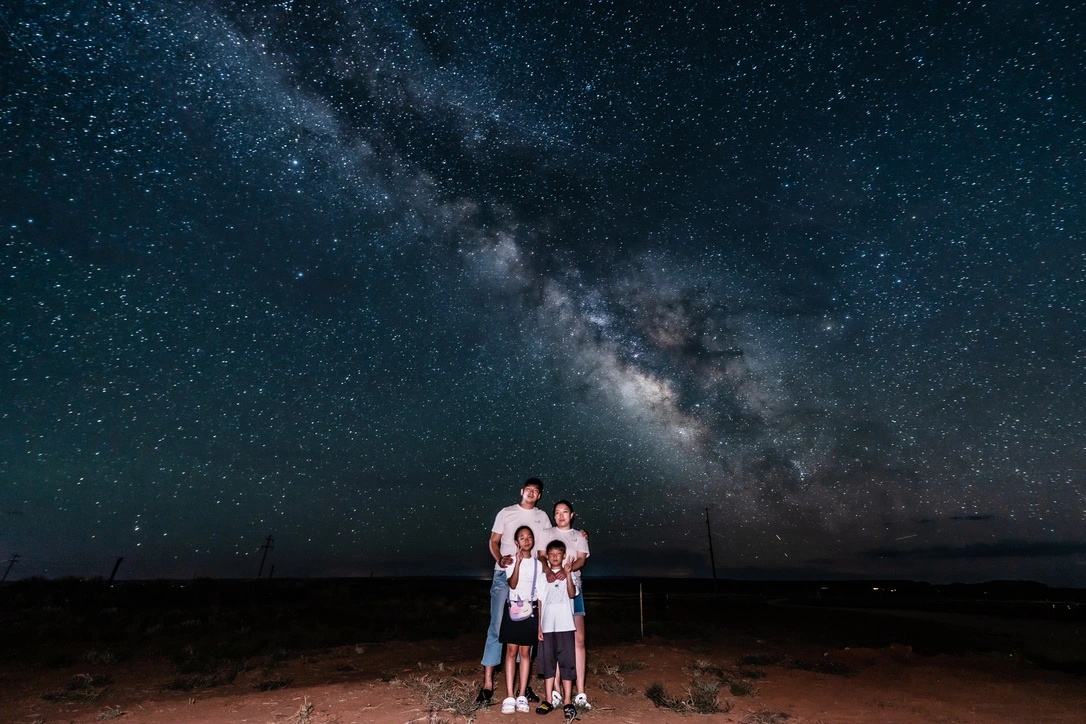 A family of four standing beneath the Milky Way