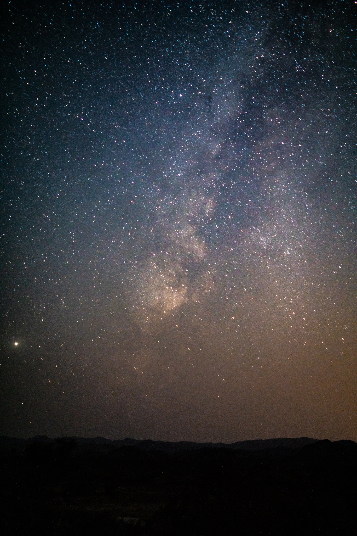 The Milky Way rising above dark desert hills