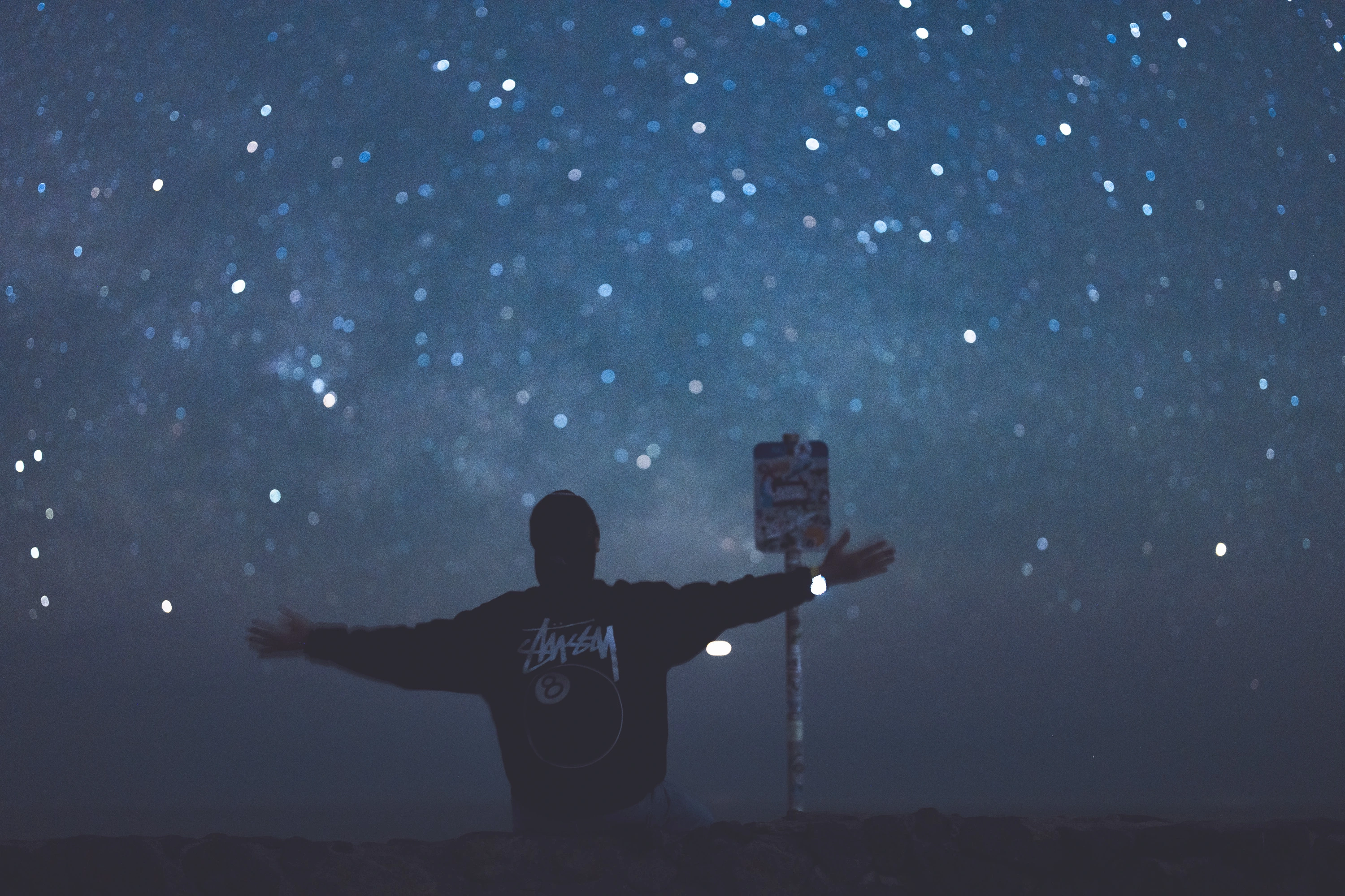 A silhouetted figure with open arms against softly blurred stars