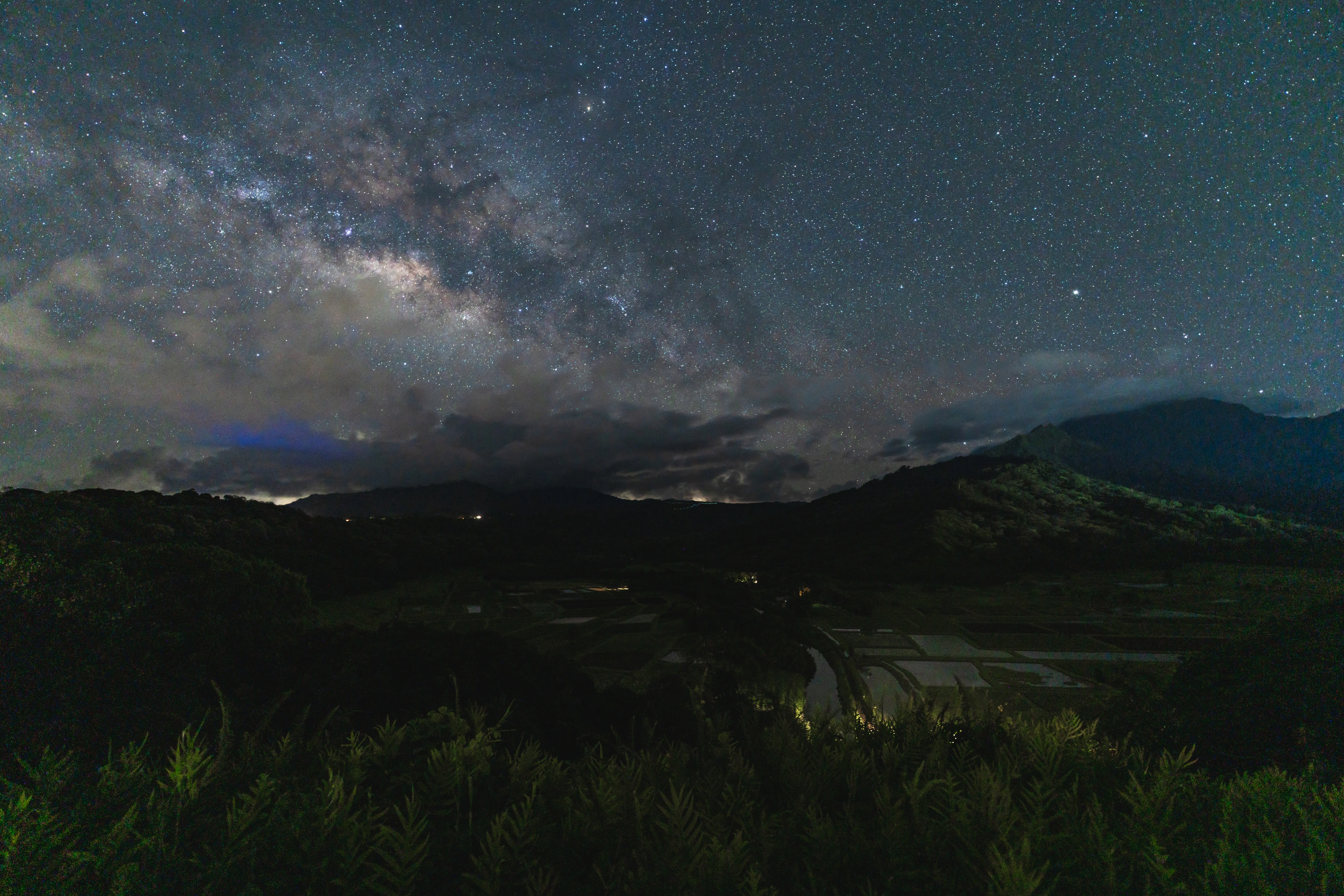 The Milky Way and clouds above the dark fields of Hanalei Valley