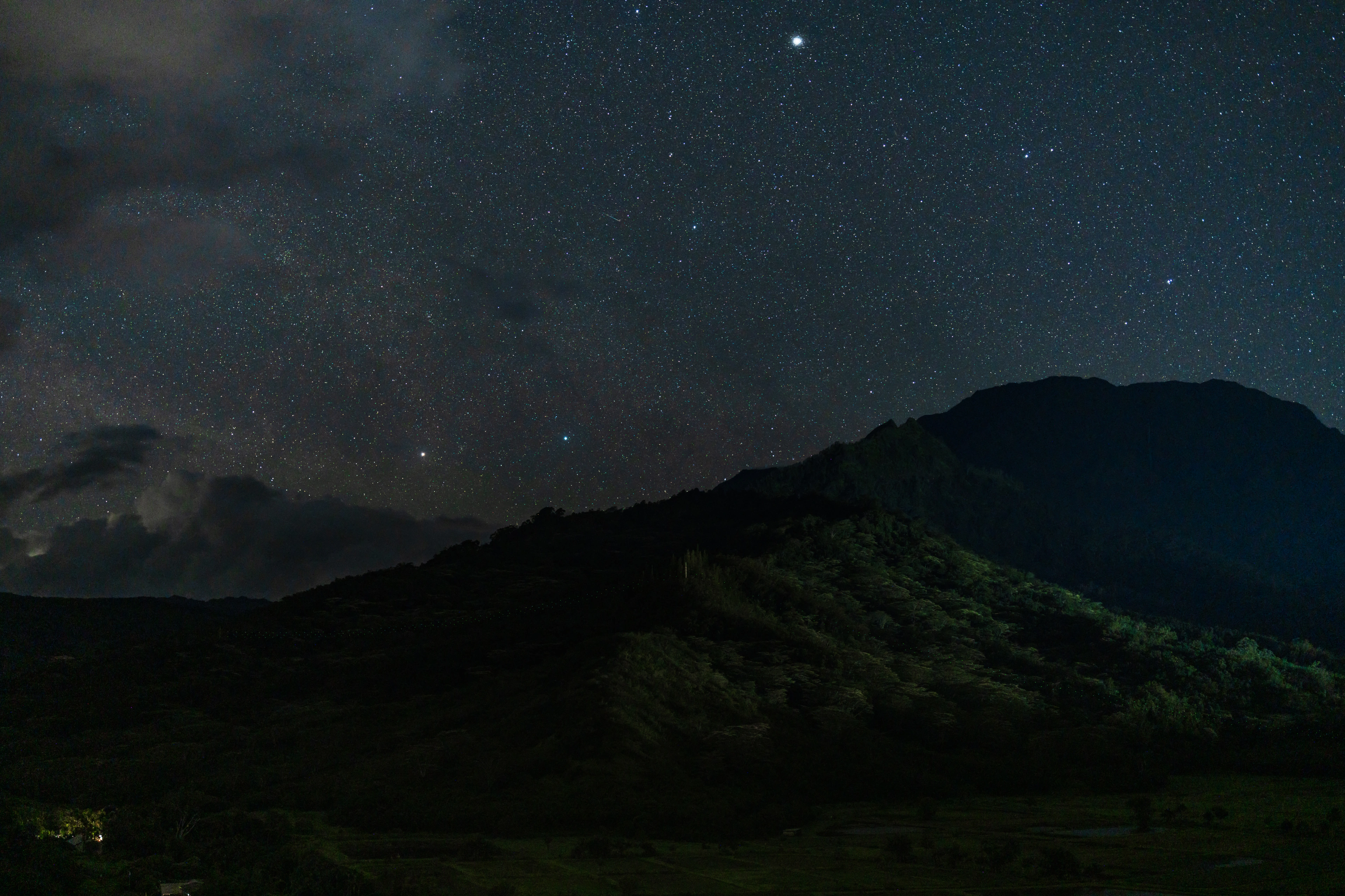 A green mountain ridge beneath stars above Hanalei Valley