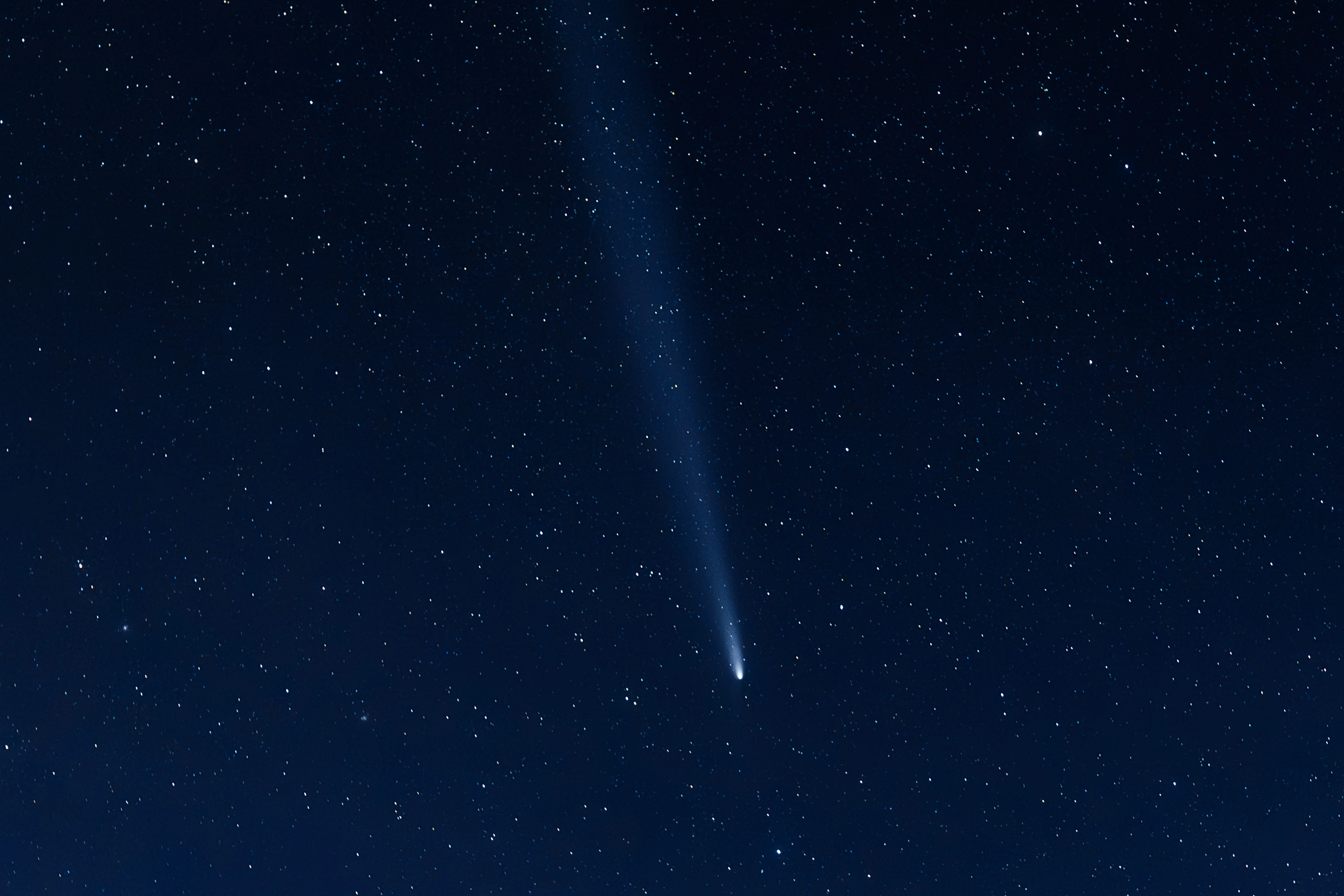 A bright comet and its long tail crossing a field of stars