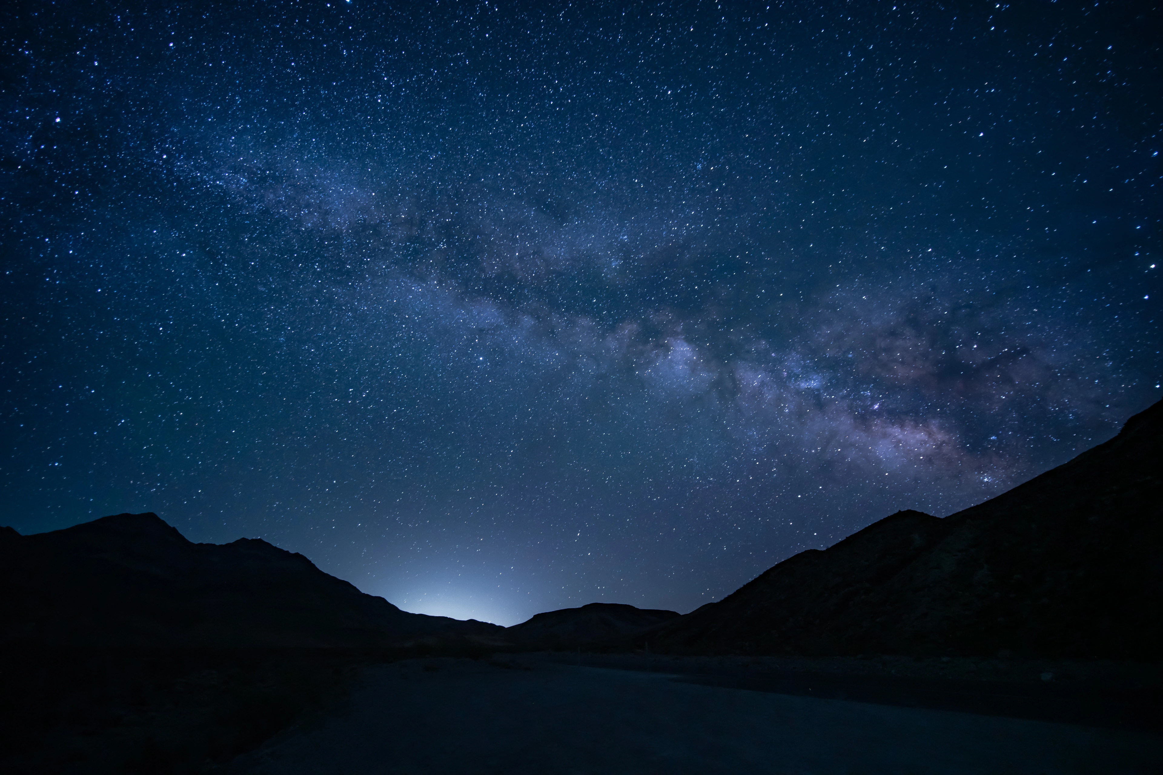 The Milky Way arching over dark desert ridges