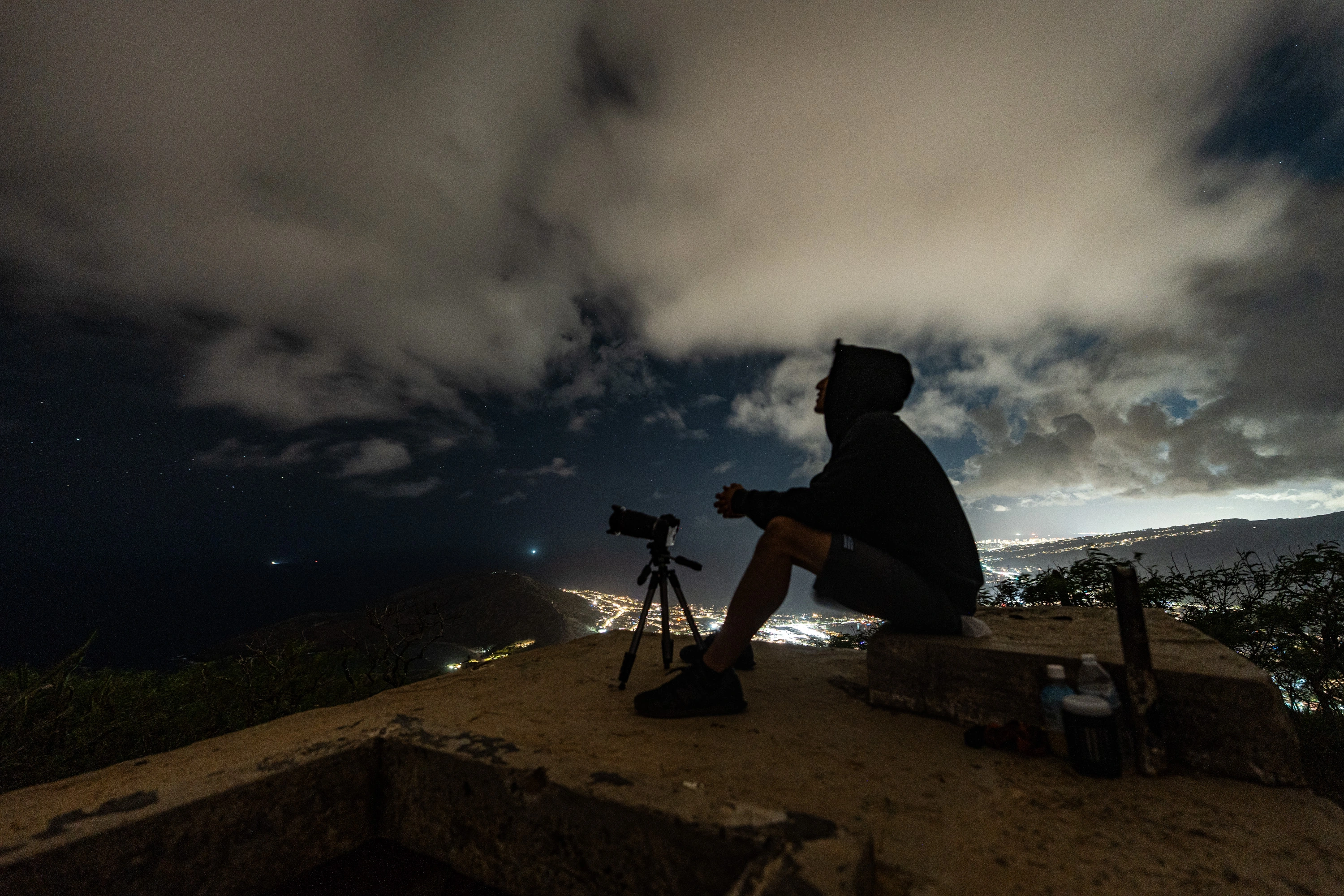 Two people beside a tripod above the lights of Honolulu