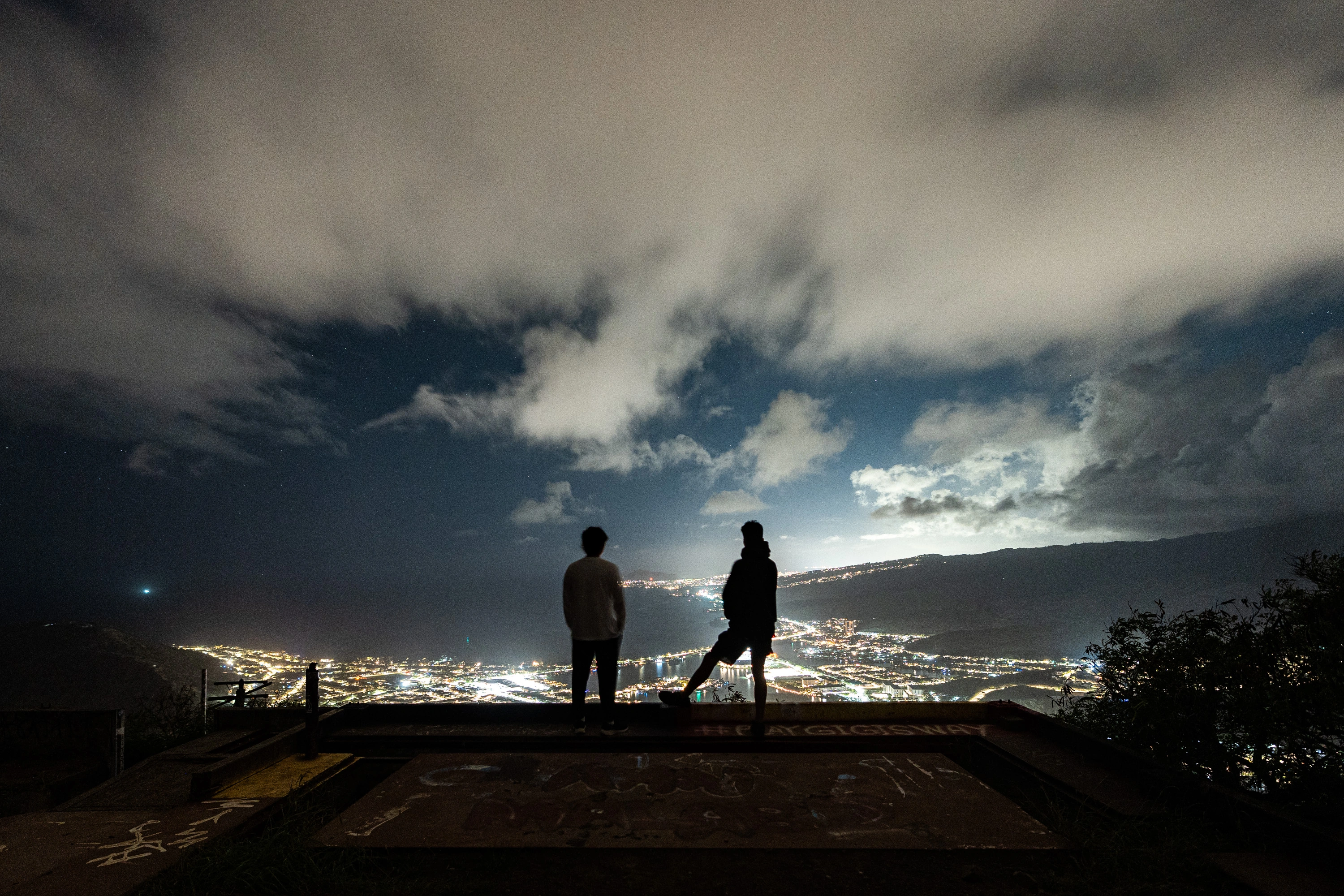 Two figures above the city lights at Koko Head