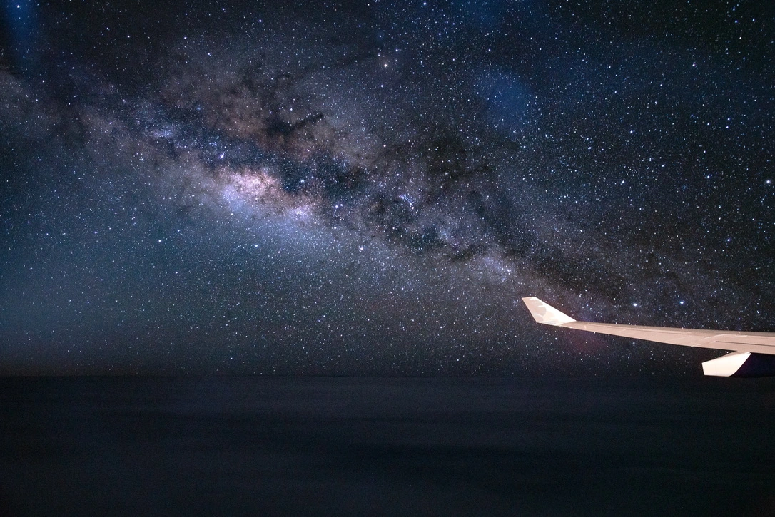 An airplane wing beneath the Milky Way over the Pacific