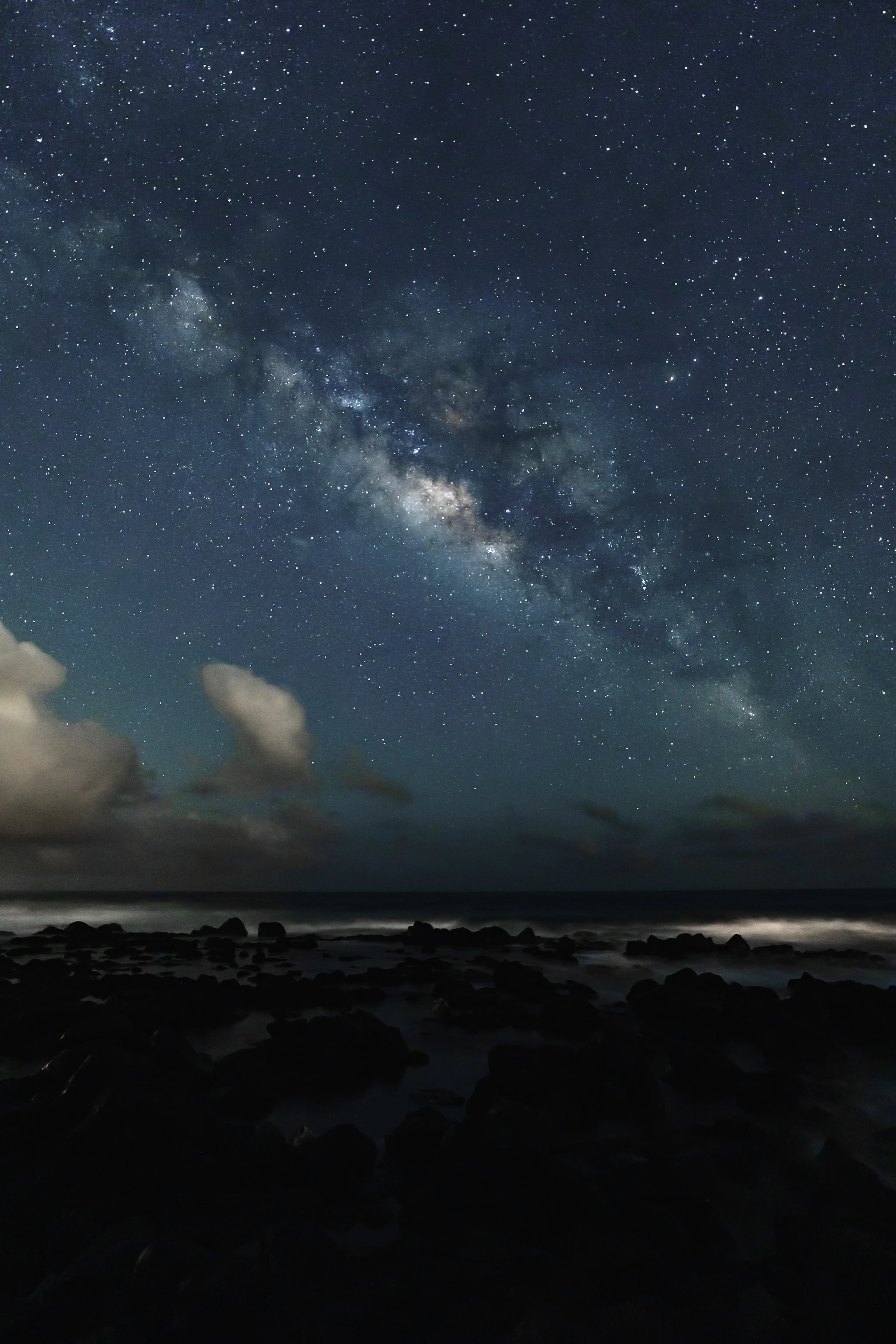The Milky Way and clouds above the dark ocean at Poipu