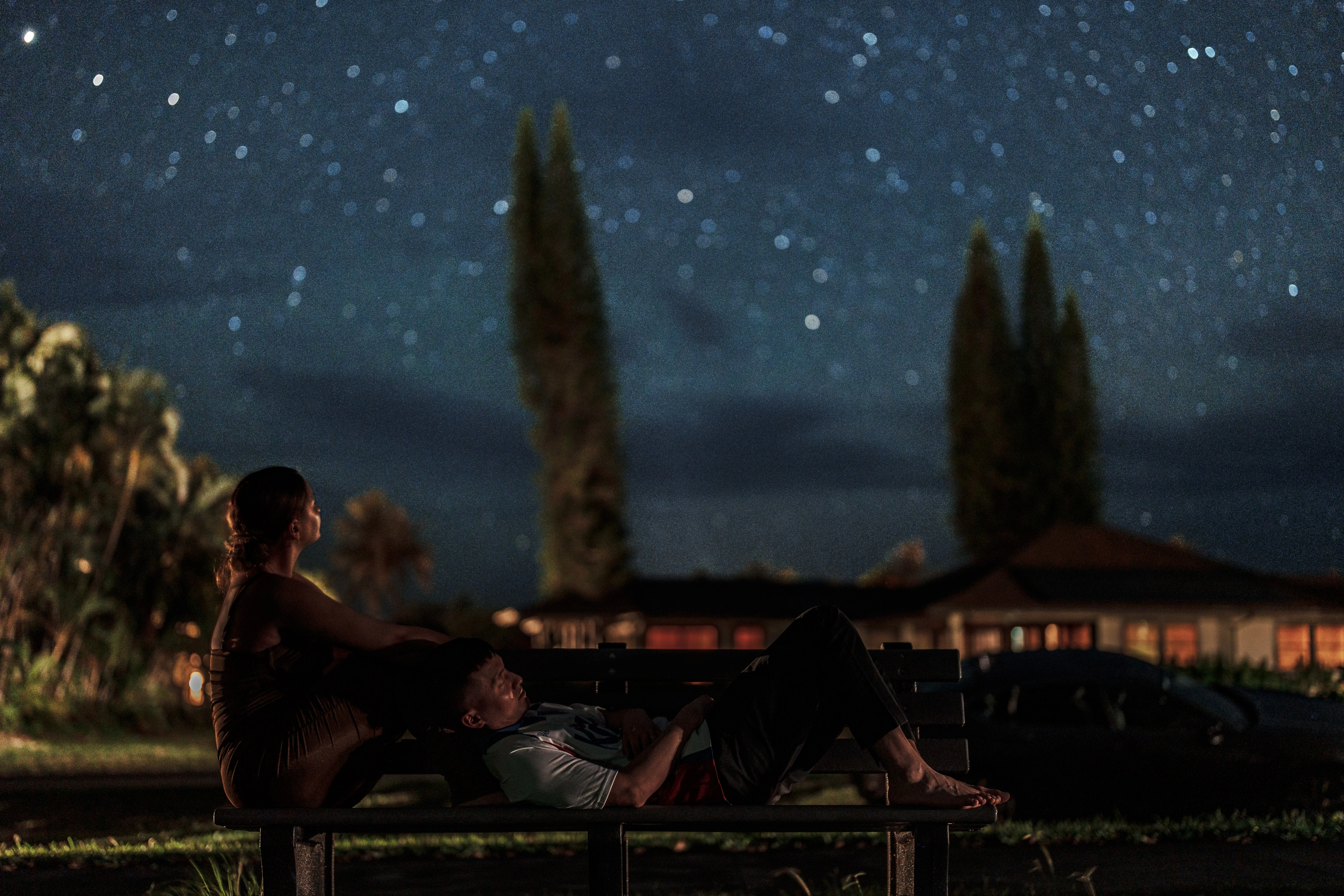 Ashley looking at the stars while Antonio rests across a bench in Princeville