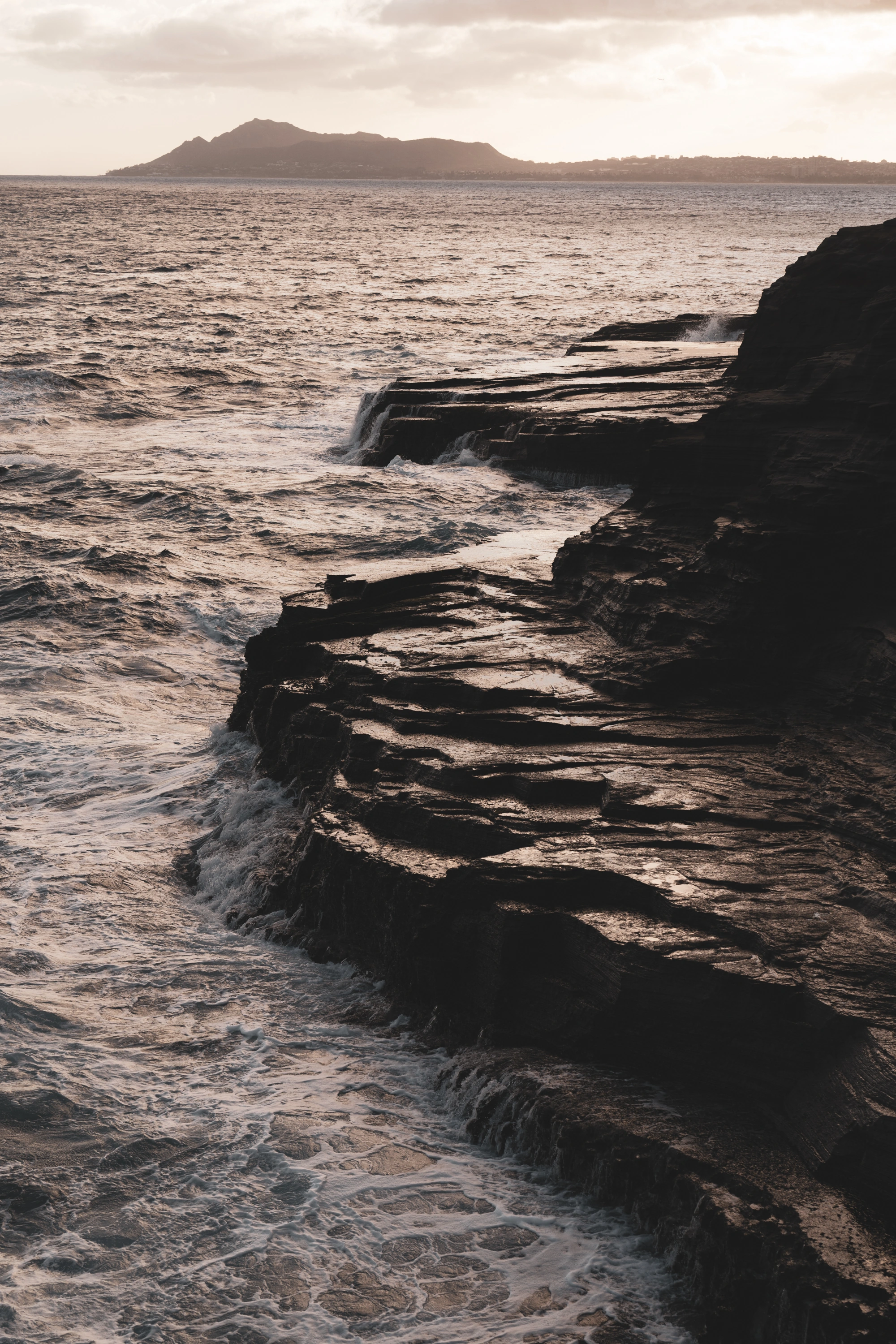 Dark rock ledges meeting the Pacific at Spitting Caves