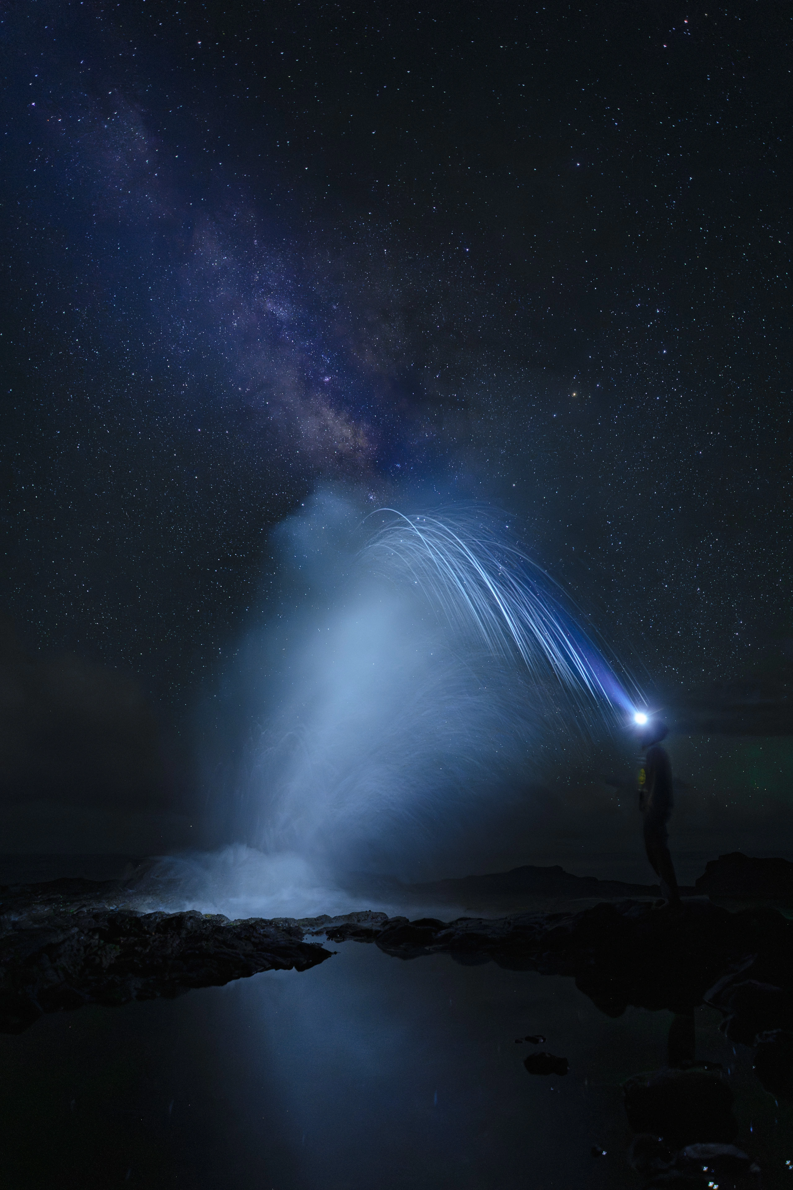 An illuminated arc of water at Spouting Horn beneath the Milky Way