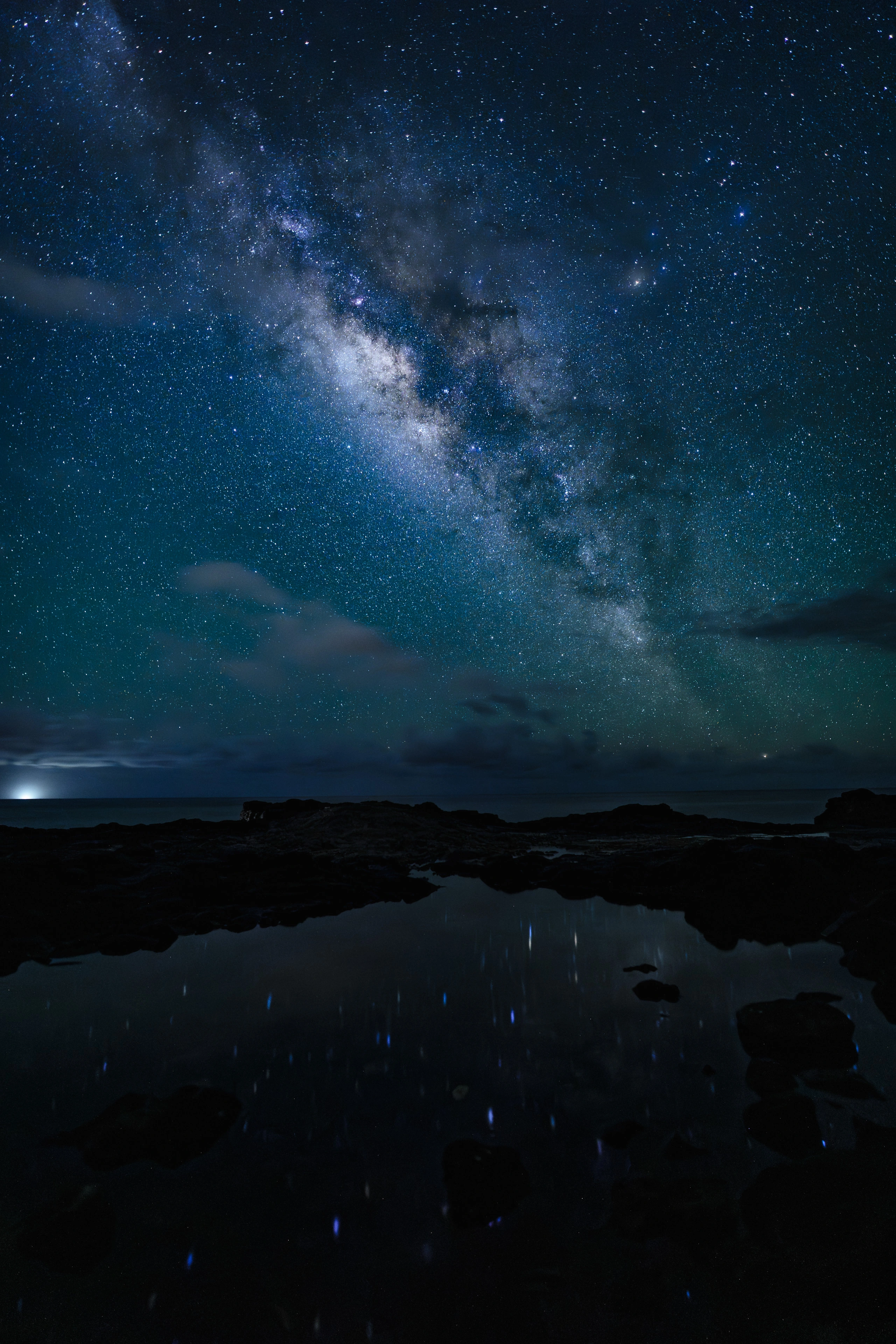 The Milky Way reflected in a dark tide pool at Spouting Horn