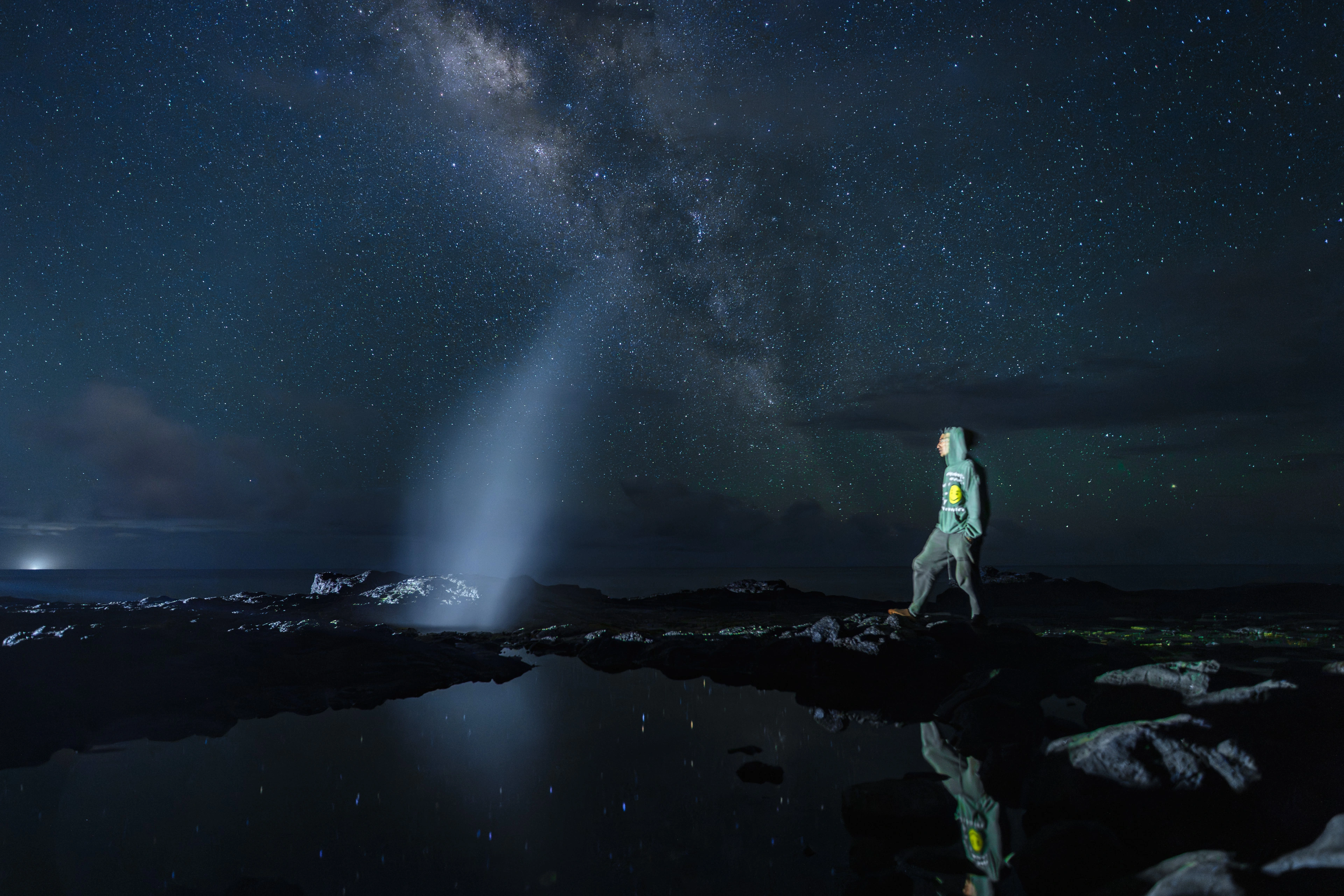 David walking beside a small eruption at Spouting Horn beneath the Milky Way