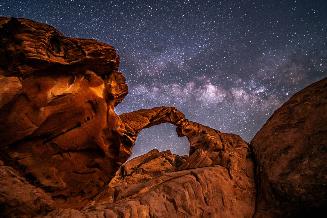 A red stone arch beneath the Milky Way