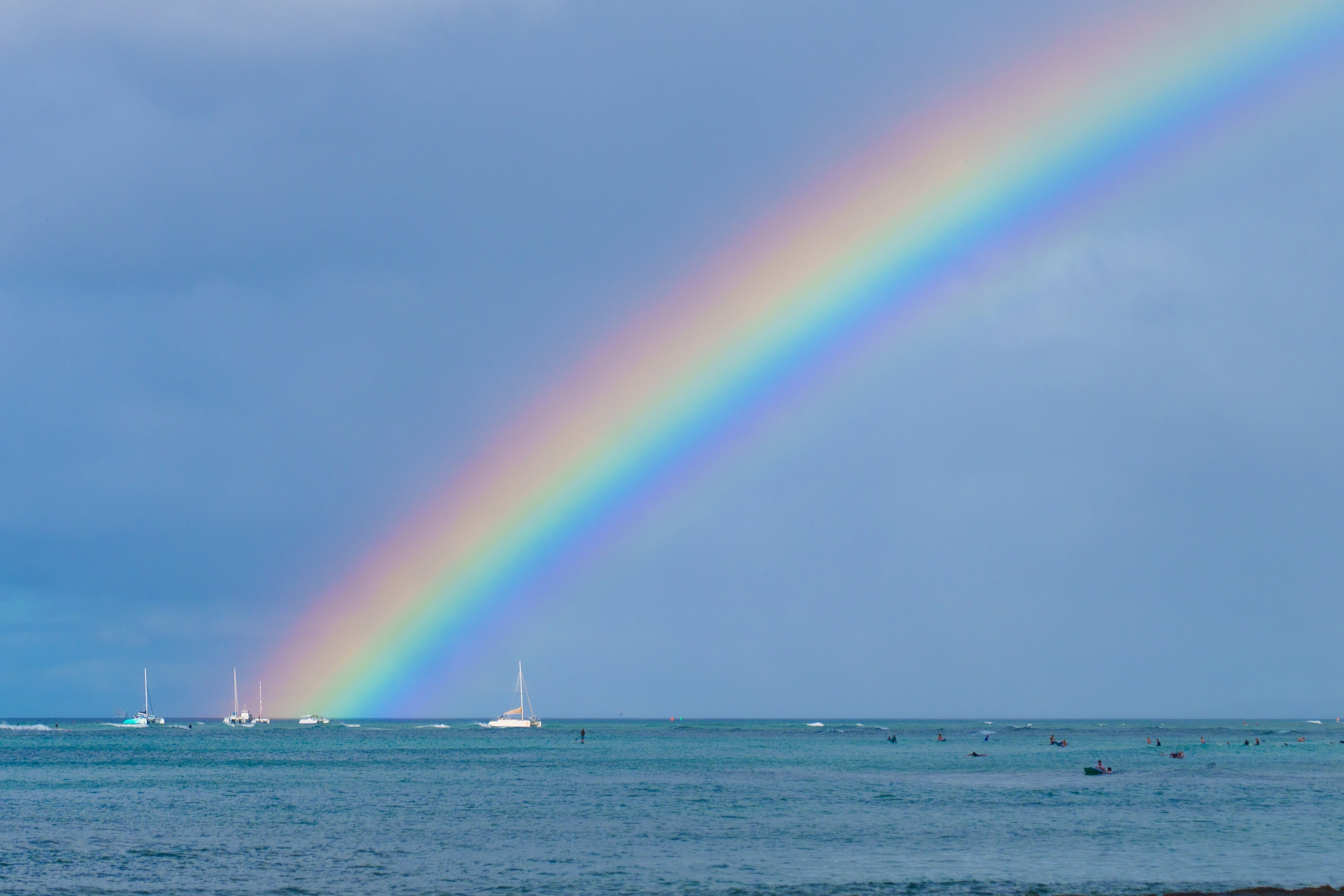 A bright rainbow descending into the ocean at Waikīkī