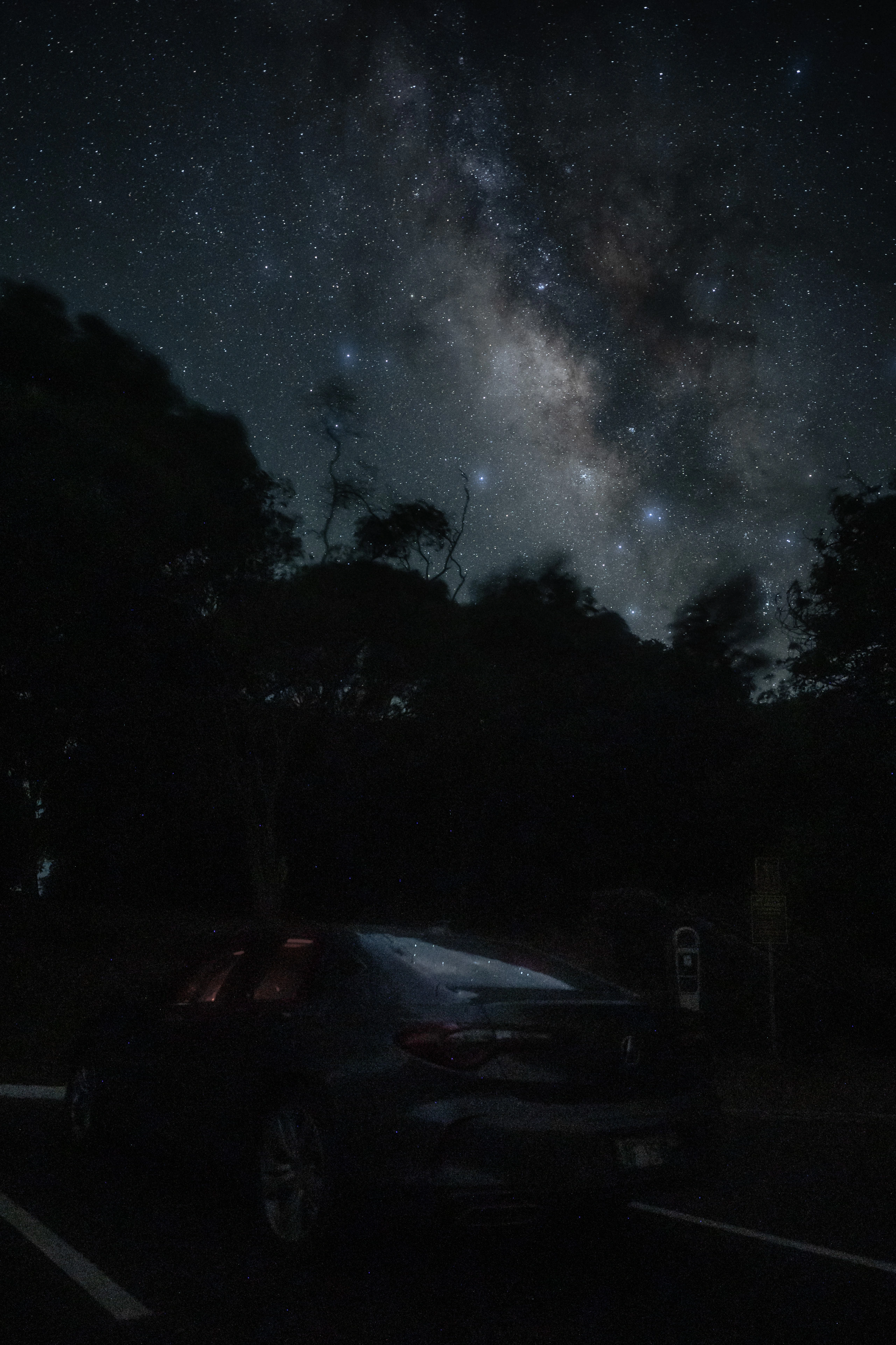 A parked car below the Milky Way near Waimea Canyon