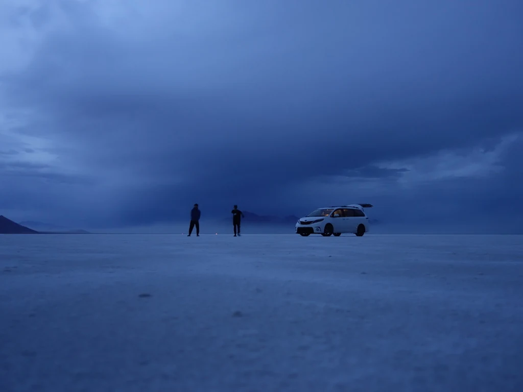 Two people and a white van on the Bonneville Salt Flats at blue hour